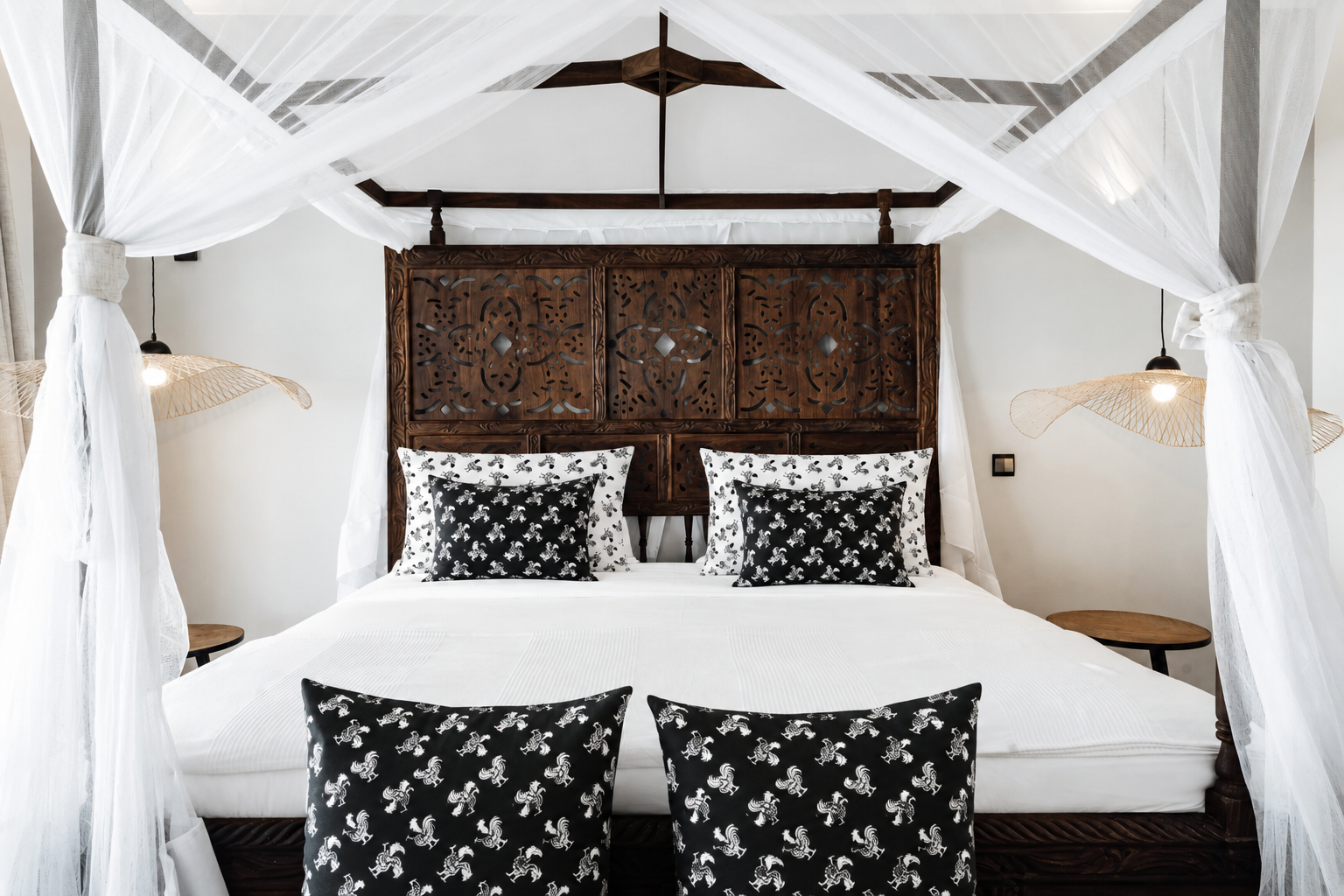 Mixed Charmed Life HOME Co. patterned pillows styled on white bedding and island-inspired decor.